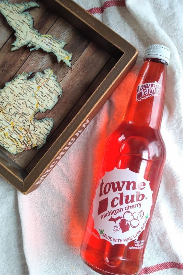 A bottle of Towne Club Michigan Cherry next to a wood Michigan map.