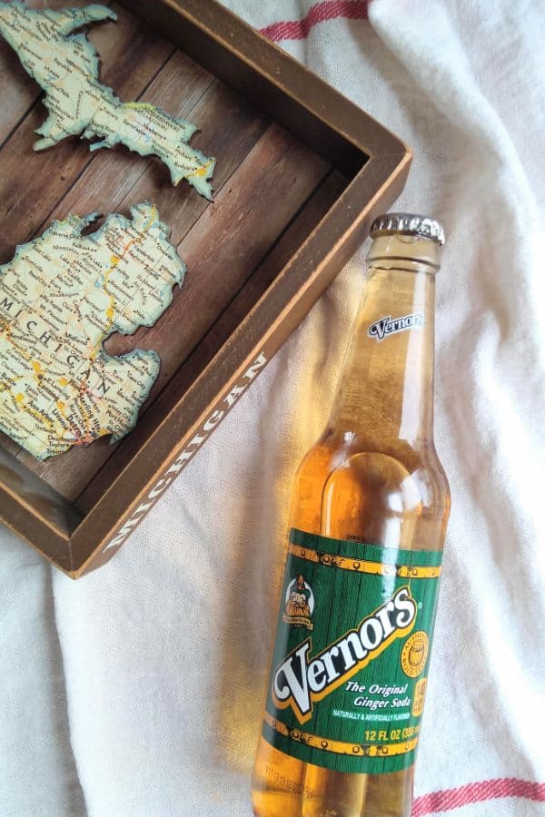 A bottle of Vernors next to a wood Michigan map.