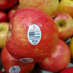 A display of WildTwist apples with one apple turn on its side to show its PLU sticker number of 3519 and that it was grown in the USA.