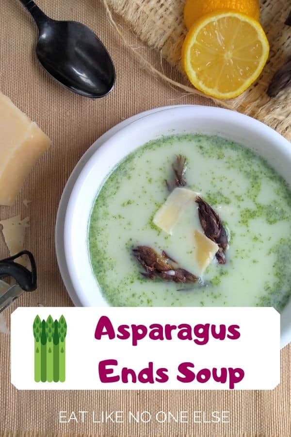 Asparagus Ends Soup in a white bowl with a black spoon and lemon wedge in the background