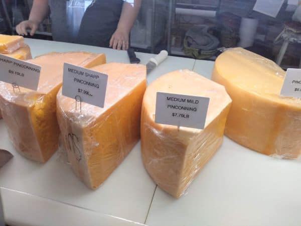 A store case with large cuts of Pinconning cheese in medium mild, medium sharp and sharp