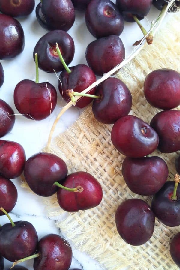 Bing cherries on a small piece of burlap sitting on top of a white background