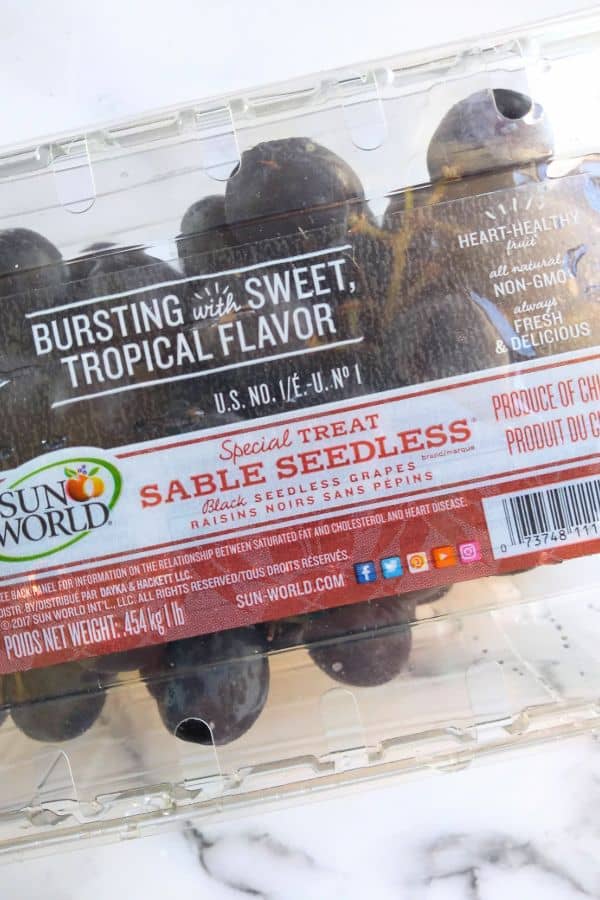 Sable Seedless grapes inside a plastic clam shell container