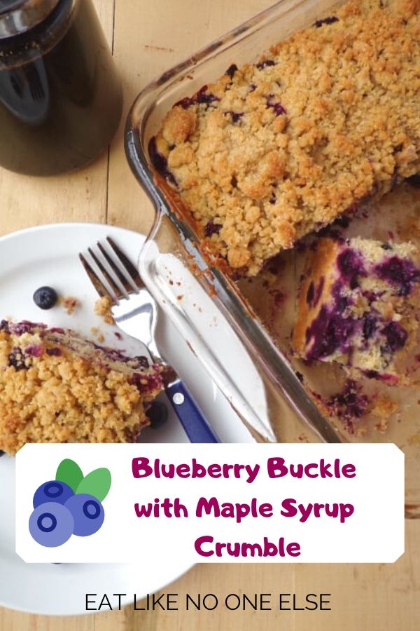 Blueberry Buckle slice on a plate with the buckle in a glass pan next to it with the words "Blueberry Buckle with Maple Syrup Crumble" at the bottom