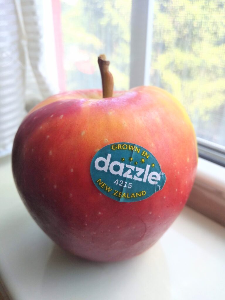 A single Dazzle apple sitting on a shelf in a window sill