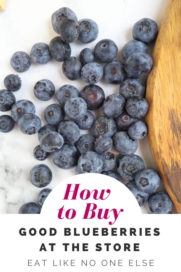 Blueberries on a white background with a wood board to the right with the words "How to Buy Good Blueberries at the Store" at the bottom