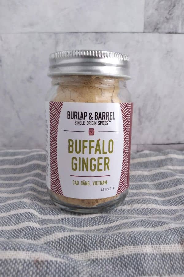 A jar of Burlap & Barrel Buffalo Ginger sitting on a gray striped towel.