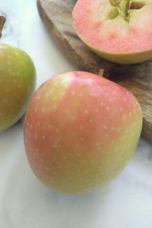 Hidden Rose apples with one apple sliced in half showing it's pink flesh.