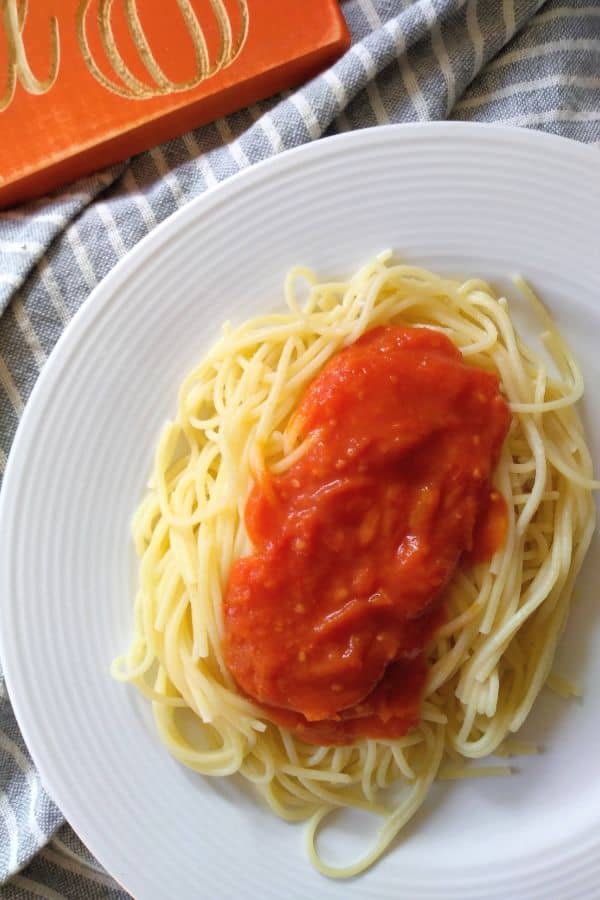 Pumpkin Spaghetti sauce is on top of a pasta sitting on a white plate.