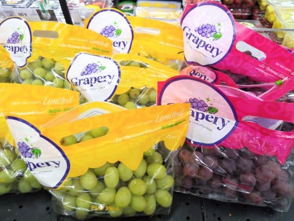 A grocery store display with Grapery Green Limited bags on left side and Red Limited bags on the right side