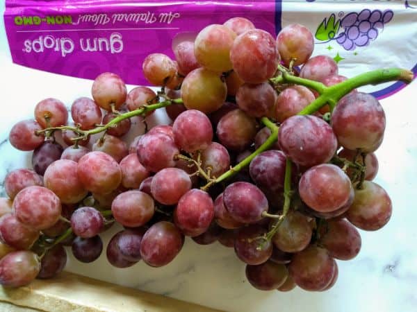 Candy Hearts Gum Drops grapes are sitting on a counter in bunches with the bag in the background