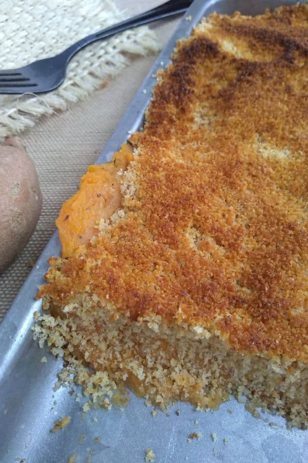 Sweet potatoes are spread onto a mini sheet pan topped with bread crumbs. The pan has just come out of the oven and the bread crumbs are toasted