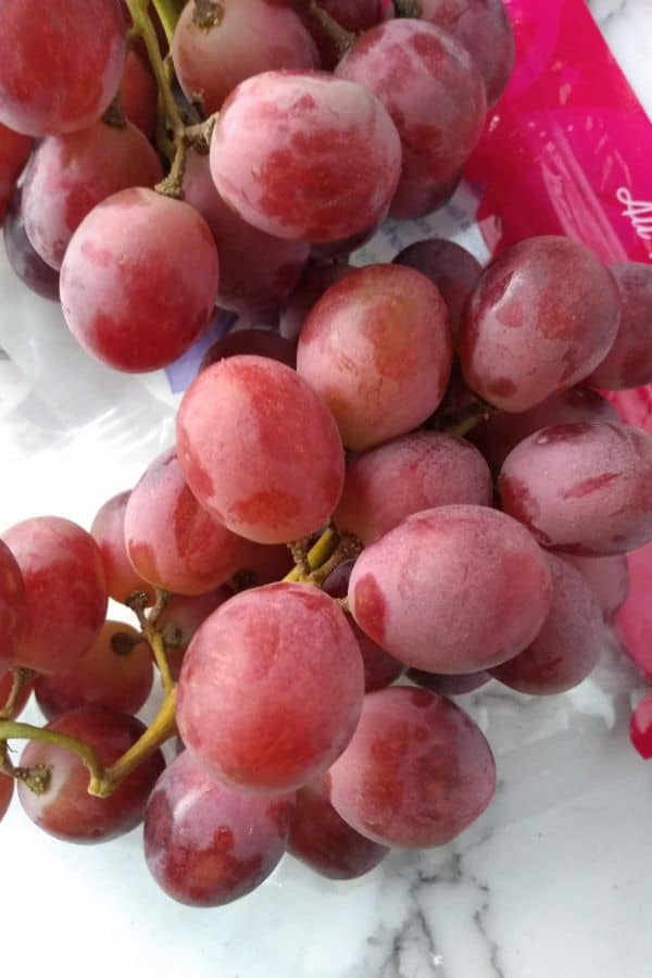 A close up view of Grapery Red Limited grapes in a bunch on top of the bag