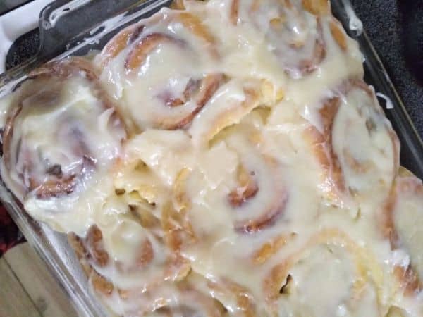 A glass pan filled with cinnamon rolls that have been frosted.