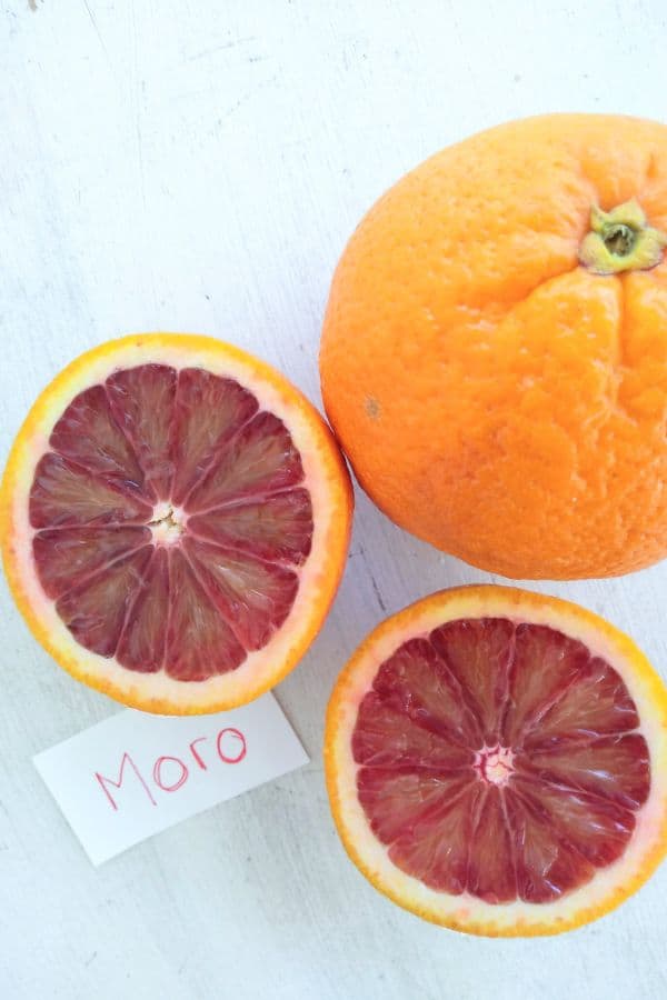 A sliced open Moro blood orange on a white board.