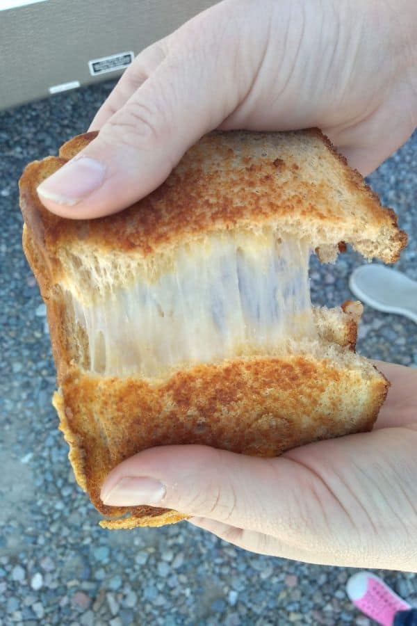 Dubliner cheese grilled cheese sandwich is cut in half and being pulled apart so you can see the cheese.