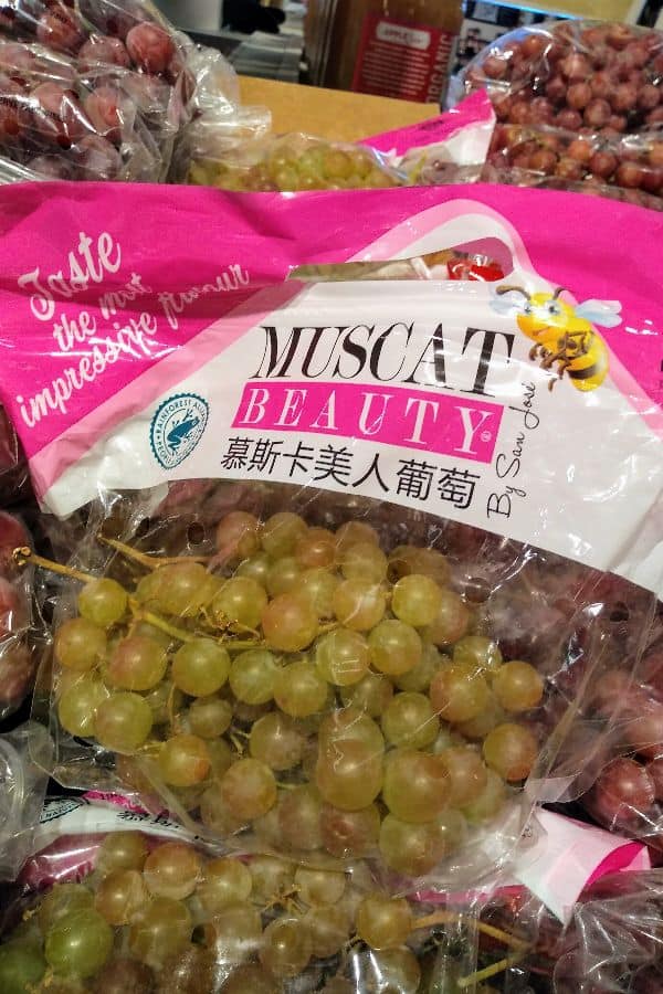 A bag of Muscat beauty grapes with a bee on it on display at a grocery store.