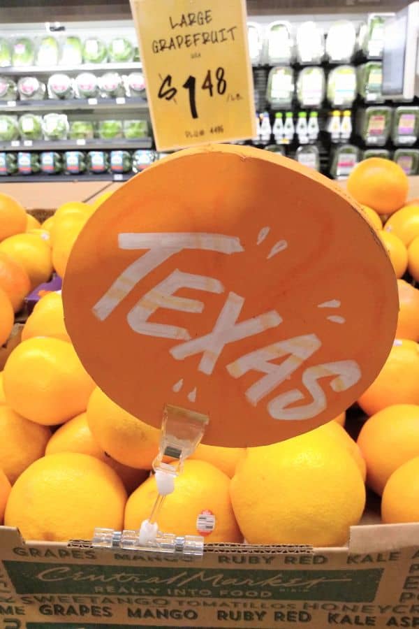 A display of Texas grapefruit at a grocery store in Texas with a Texas sign and a sign in back that says "large grapefruit $1.48/lb."