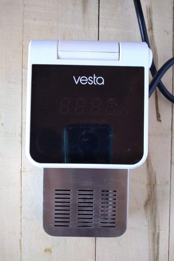A white Vesta immersion circulator sitting on a wood board.