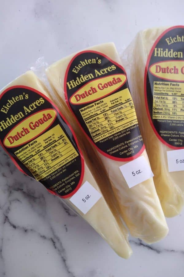 Wedges of Eichten's Hidden Acres Dutch Gouda in it's packaging on top of a white board.