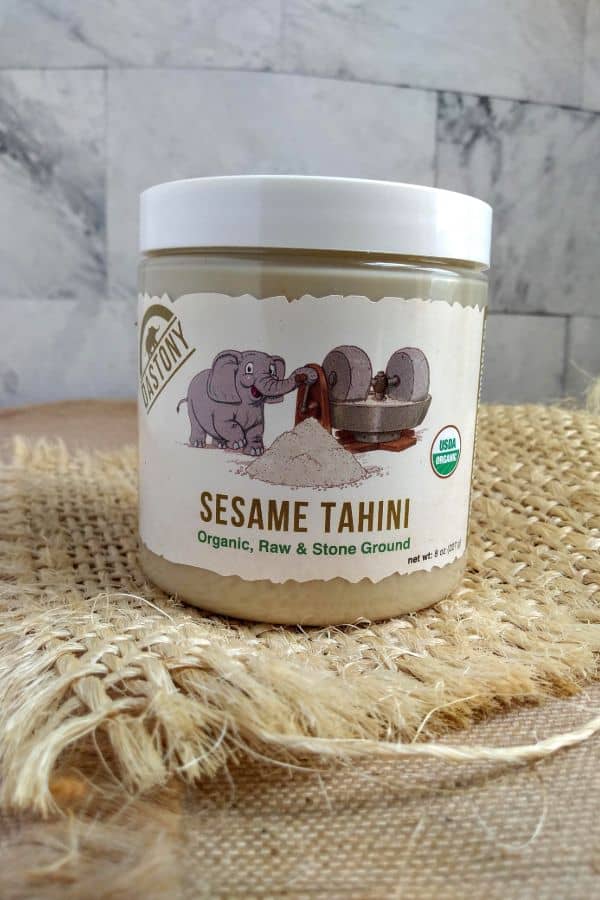 Dastony Sesame Tahini in a jar sitting on burlap on a counter top.