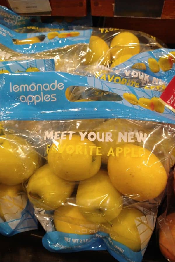 See through 2 pounds bags of lemonade apples with a blue handle on top and the phrase "meet your new favorite apple" on the bag.