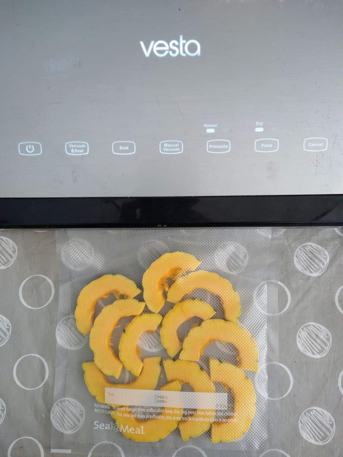 A Vesta vacuum sealing is shown with a single layer of Delicata squash ready to be sealed.