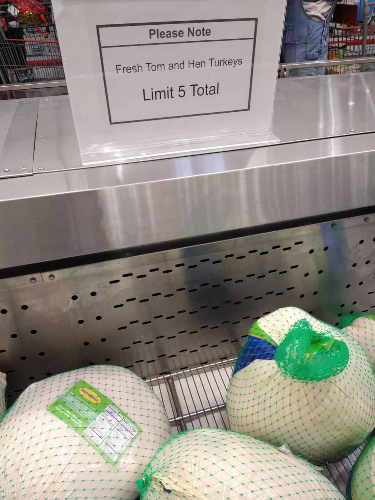 Ein weißes Schild mit schwarzem Aufdruck über einem Costco Truthahn Display sagt, dass bitte beachten Sie frische Tom und Henne Truthähne Grenze 5 Gesamt.