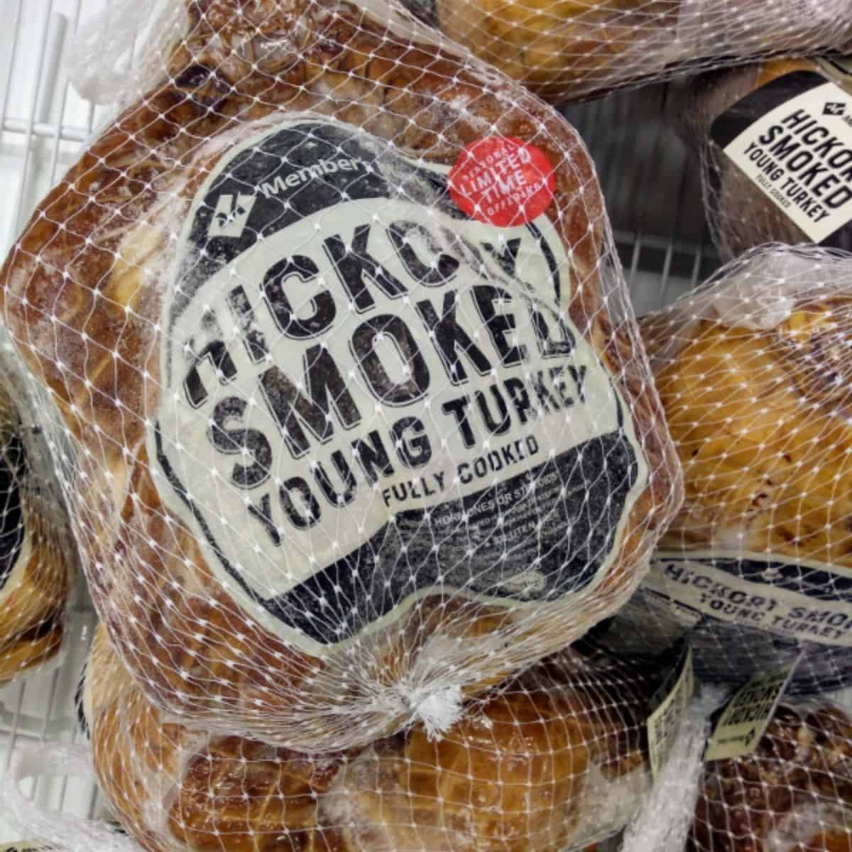 A display of Member's Mark Hickory Smoked Young Turkey in brown packaging with white netting over top.