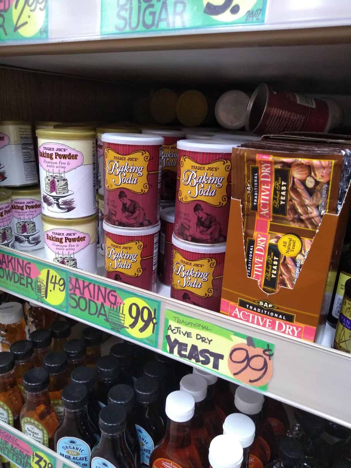 A grocery store shelf with baking powder, baking soda, and packs of active dry yeast.