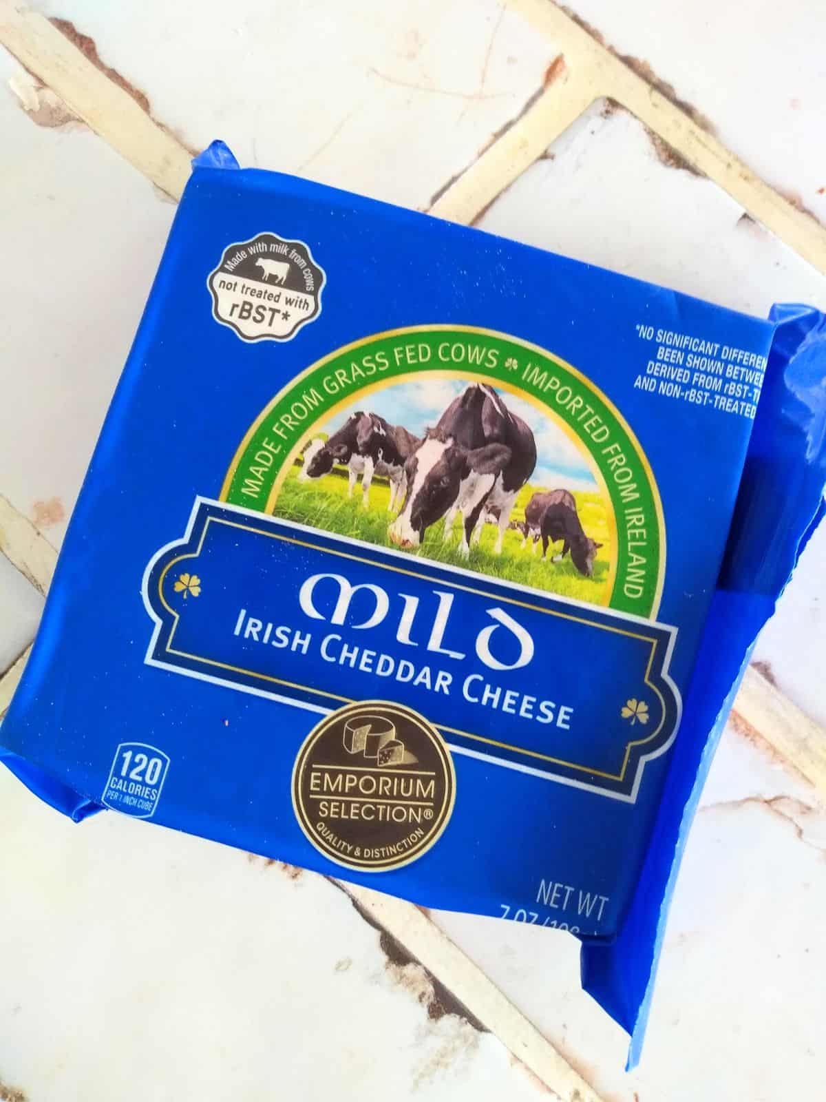 Emporium Selection Mild Irish Cheddar cheese in a blue package on a  white tile countertop