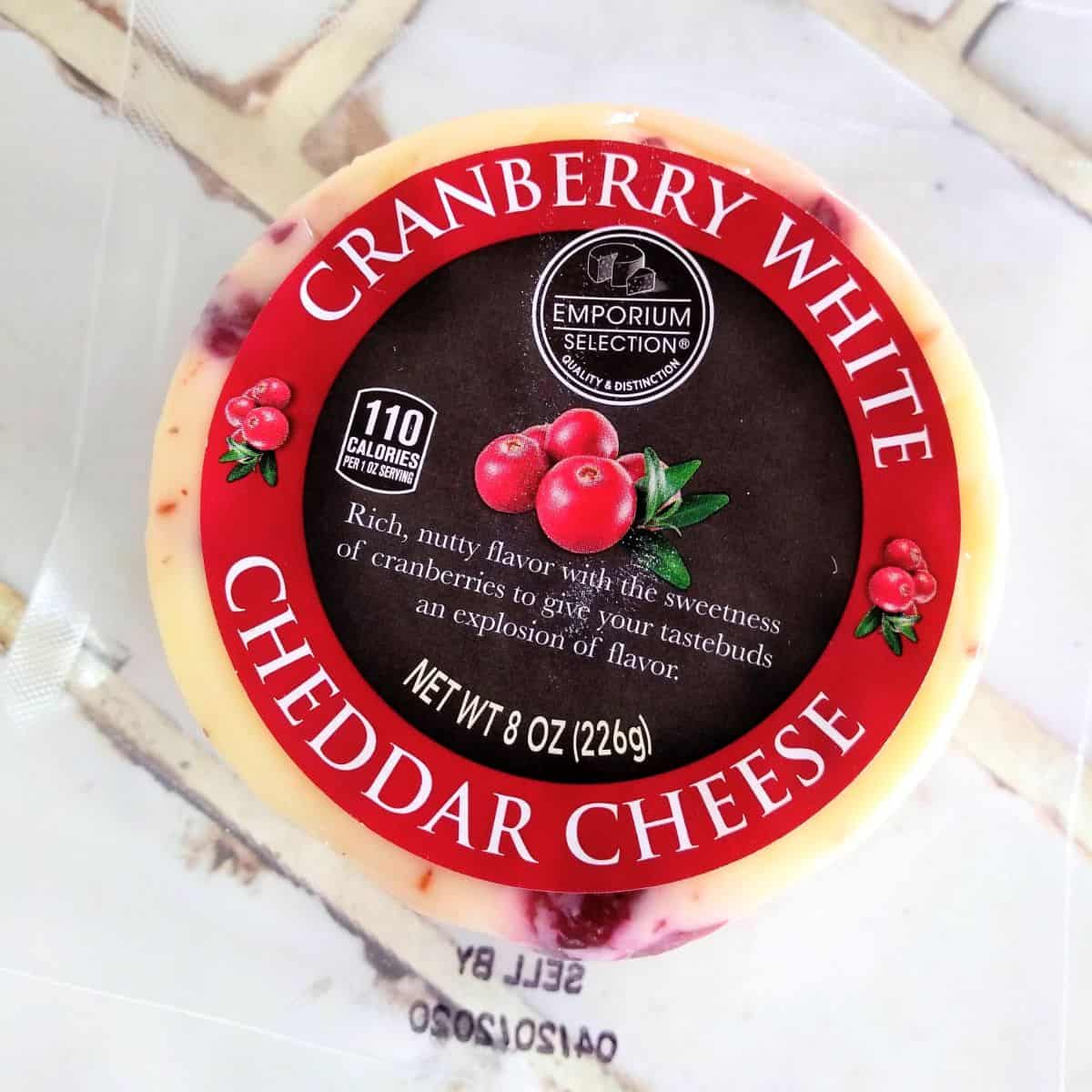 A circle of Emporium Selection Cranberry White Cheddar on a white tile countertop