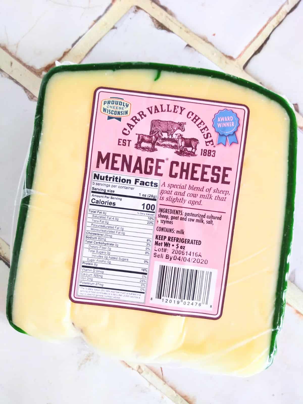 Carr Valley Menage Cheese with a green rind on a white tile countertop