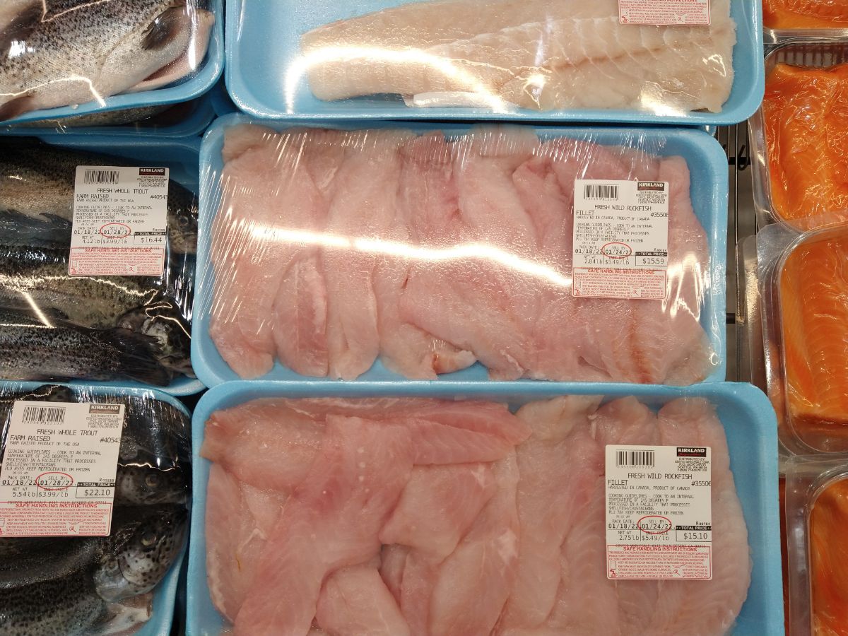 Packages of fresh wild rockfish, next to salmon, and whole trout at a Costco store.