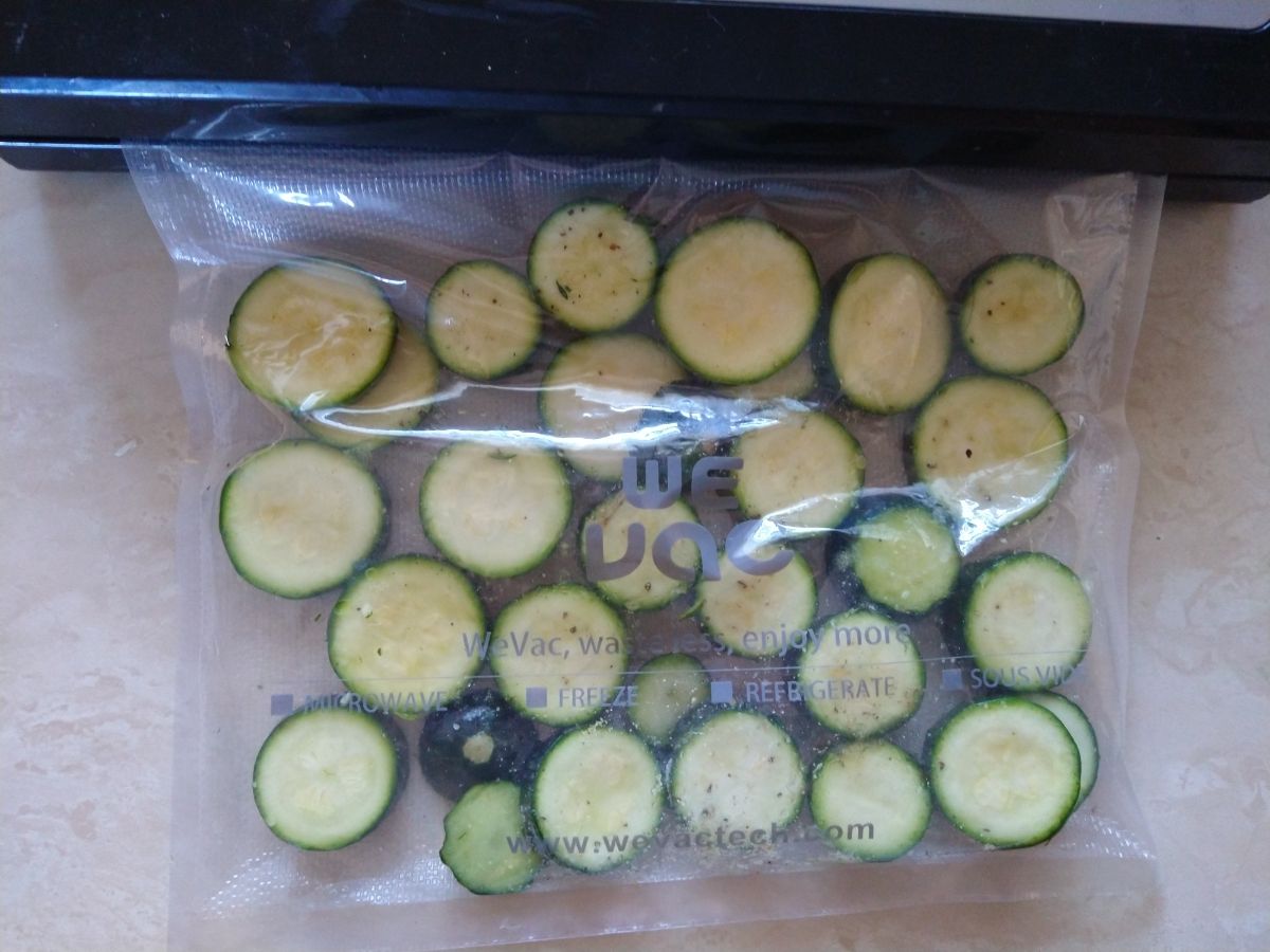 Sliced zucchini in a bag in a single layer ready to be vacuum sealed by a vacuum sealer.