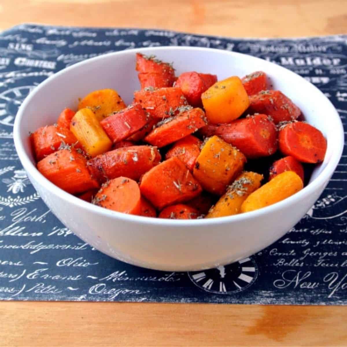 A white bowl filled with buttery roasted carrots topped with herbs.