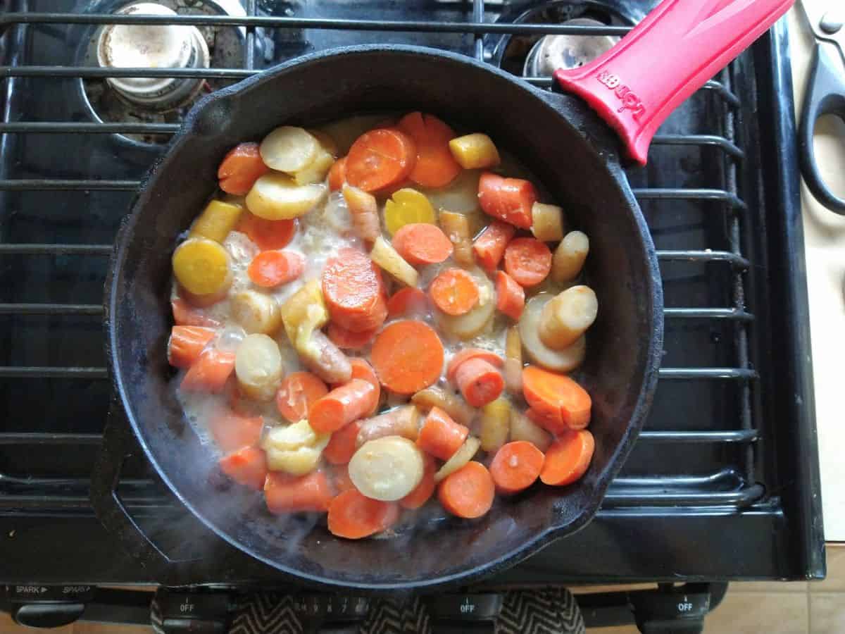 A cast iron skillet with sous vide carrots being browned in butter.