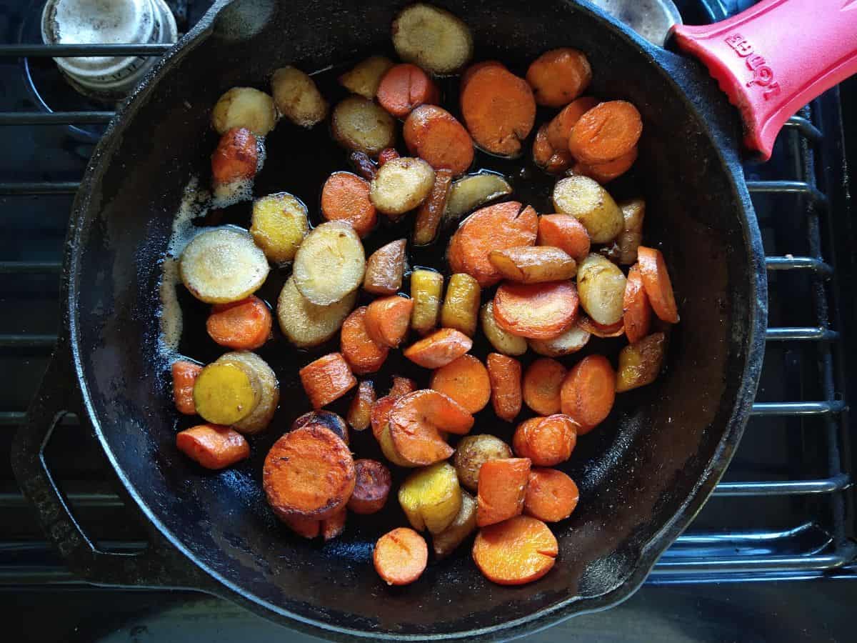 A cast iron skillet with sous vide carrots  browned in butter.