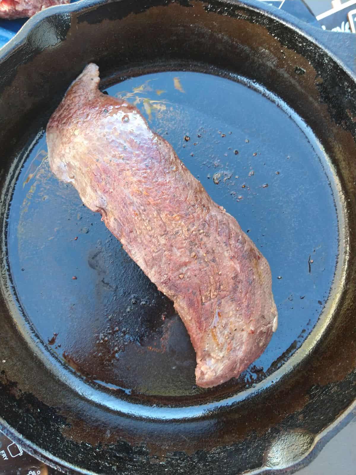 A browned Teres Major steak in a hot cast iron skillet.