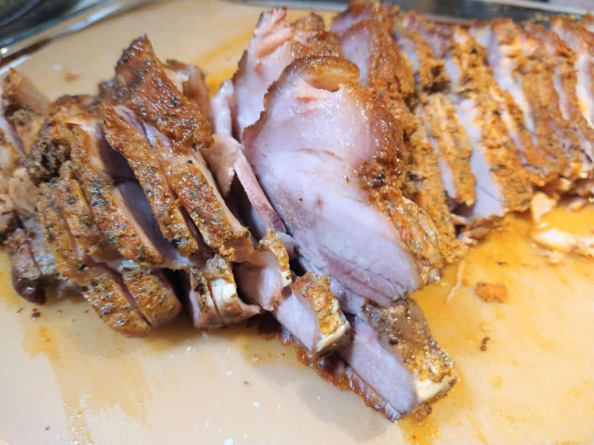 Slices of pork brisket on a wood cutting board.