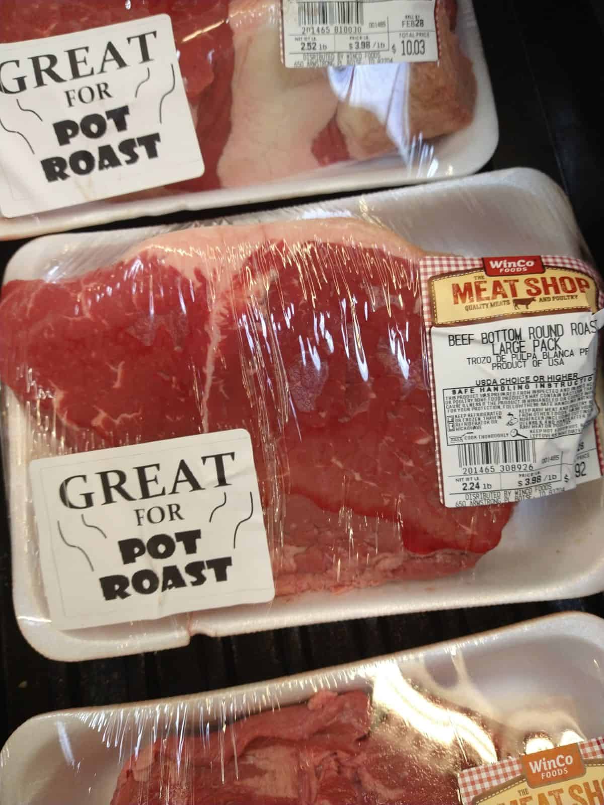 A packaged bottom round roast on display at a Winco foods store. The price is $3.98 a pound and this roast is 2.24 lbs. A sticker on the package says Great for Pot Roast.