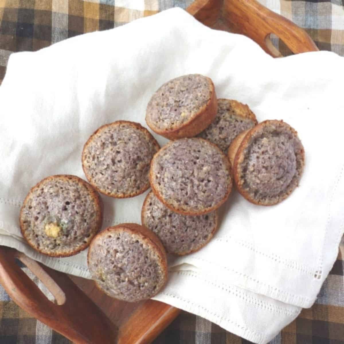 Blue cornmeal muffins on a white towel in a brown tray.