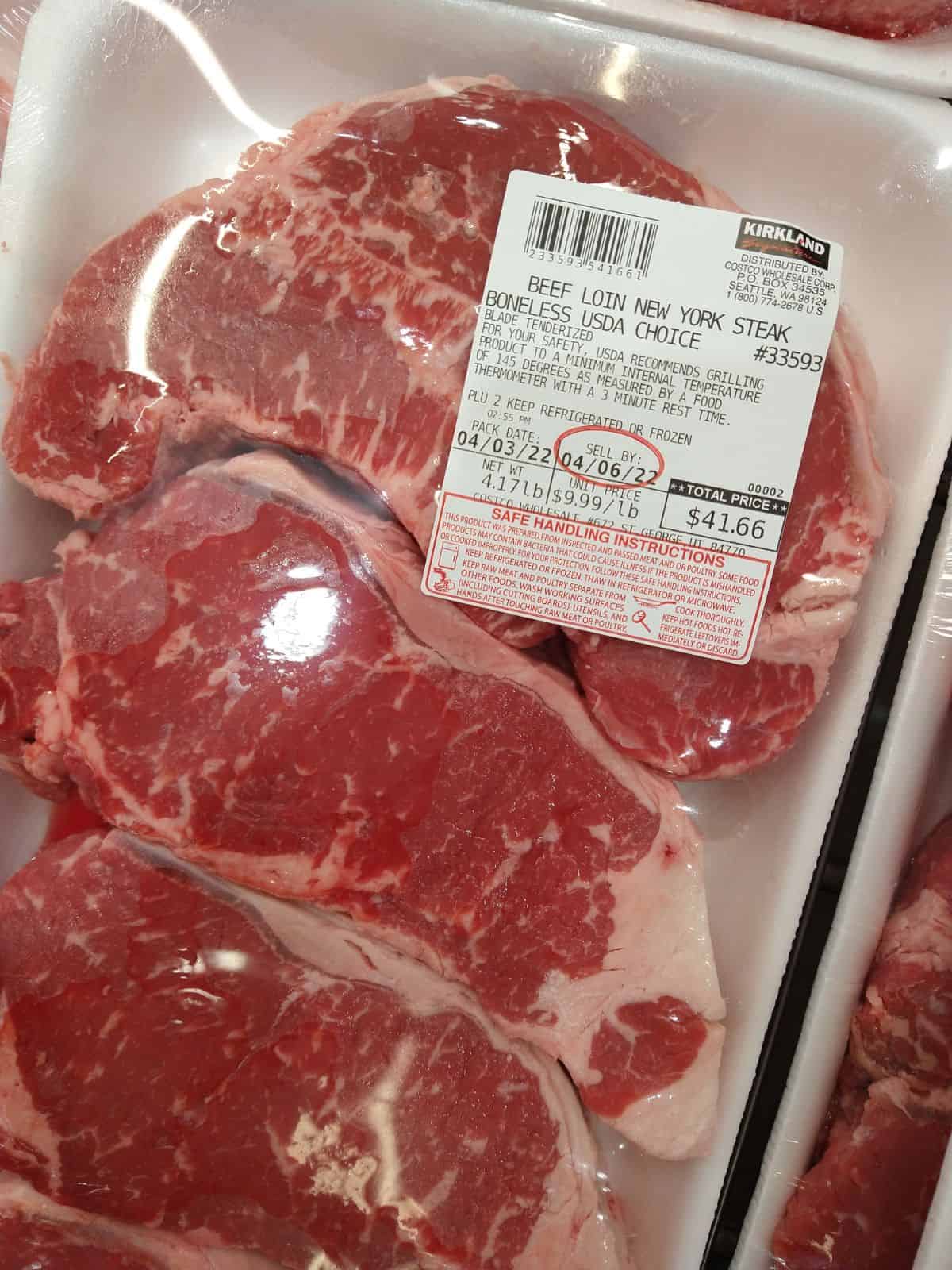 Kirkland brand New York Boneless strip steaks in a package at Costco. The price is $9.99/lb.