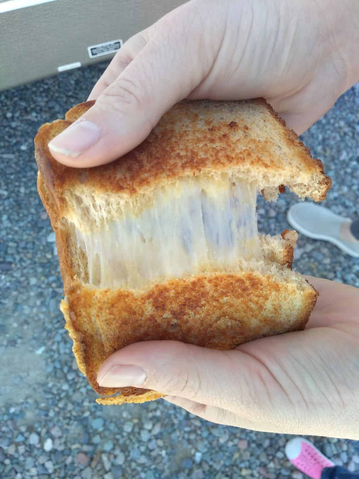 Dubliner cheese grilled cheese sandwich is cut in half and being pulled apart so you can see the cheese.