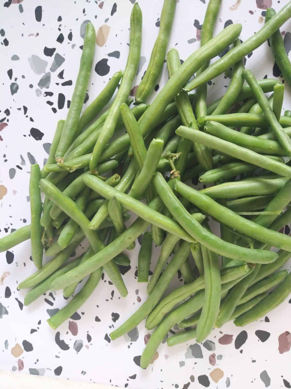 A pile of Green Beans on a white table with colored spots.