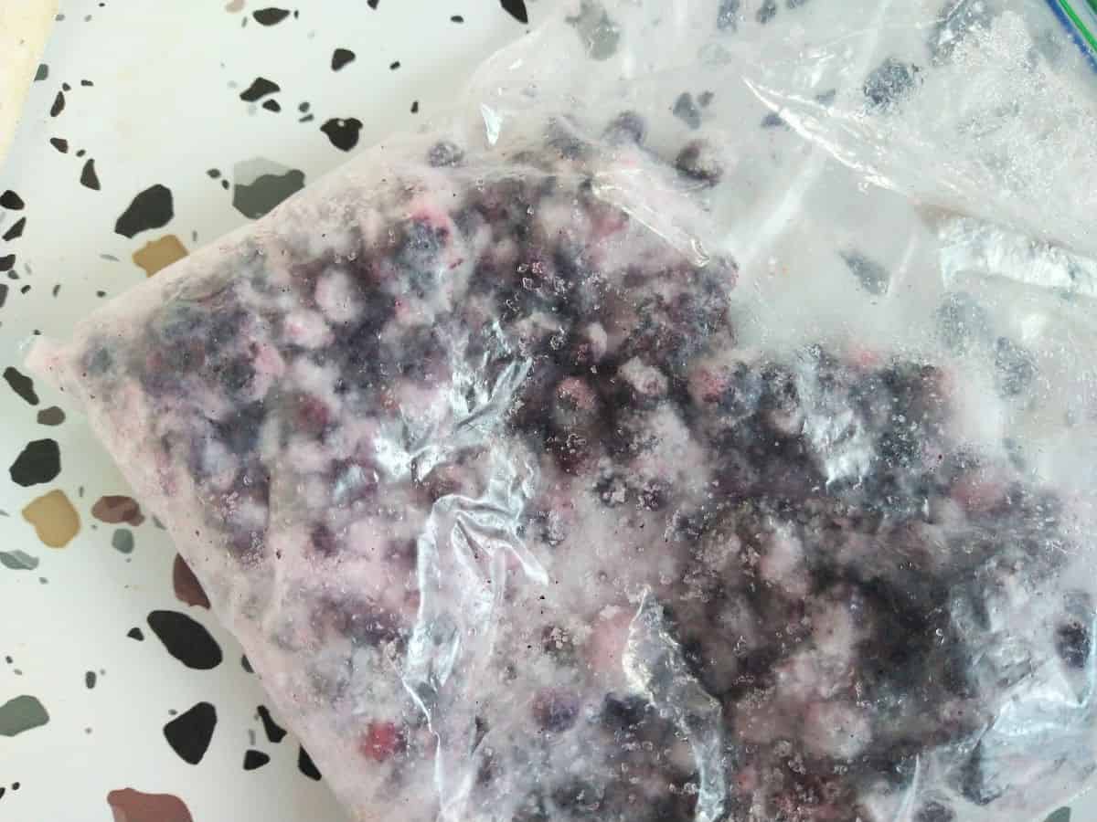 Frozen blueberries in a plastic bag sitting on a table.
