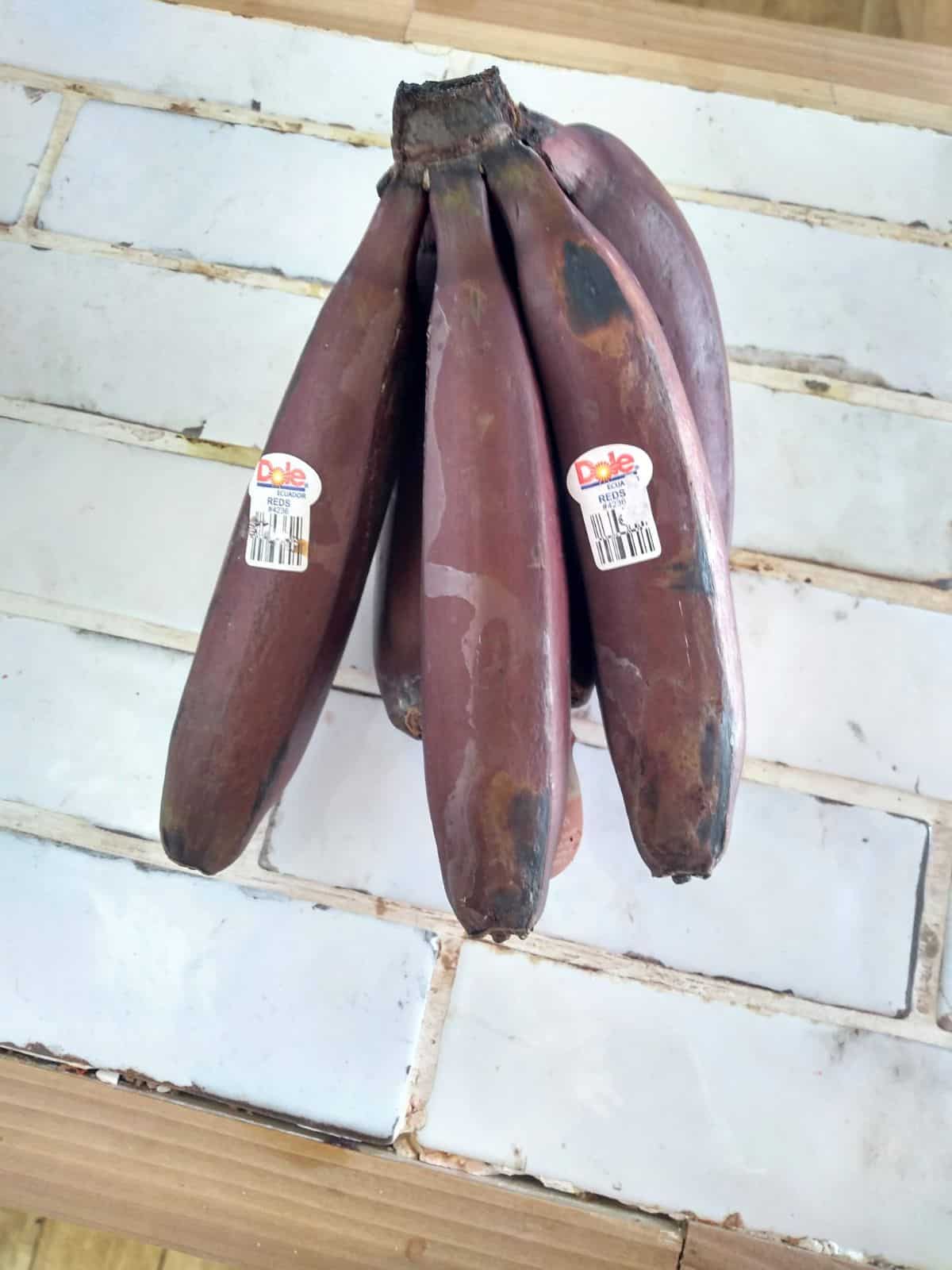 Red bananas sitting on a white tile counter top.