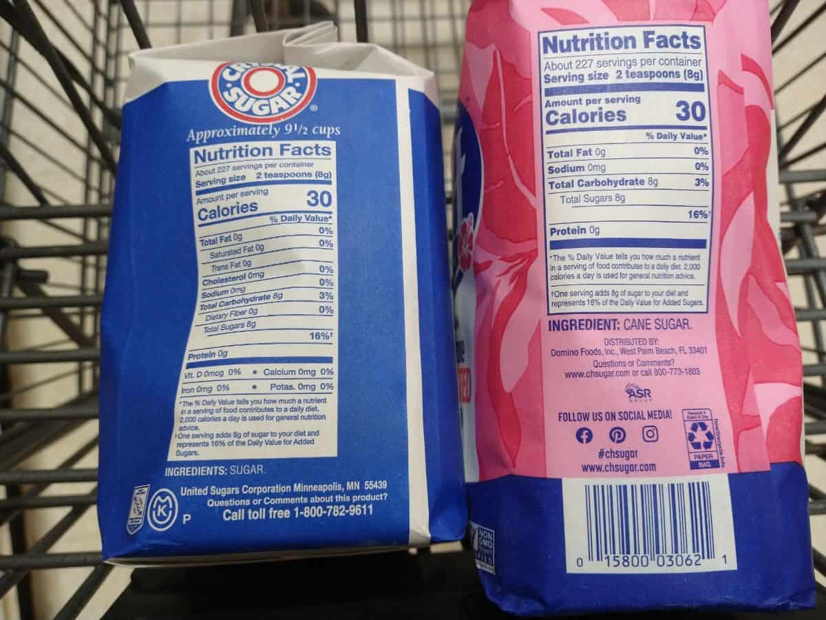 Two bags of sugar in a grocery cart. The sugar on the left just lists "sugar" as the ingredients. The sugar on the right lists "cane sugar" on the ingredients. 