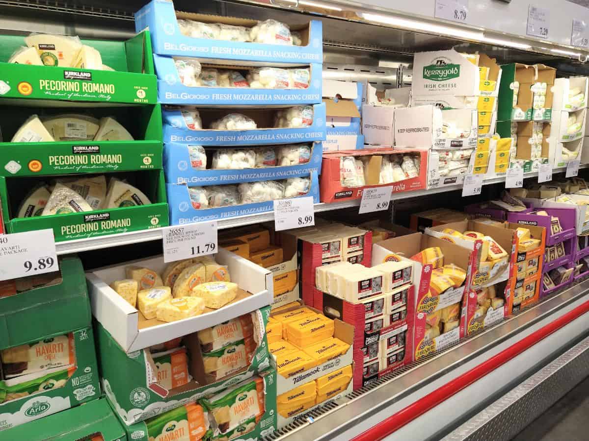 The display of different types of cheeses at a Costco store. Cheese is arranged in the box it was shipped in.