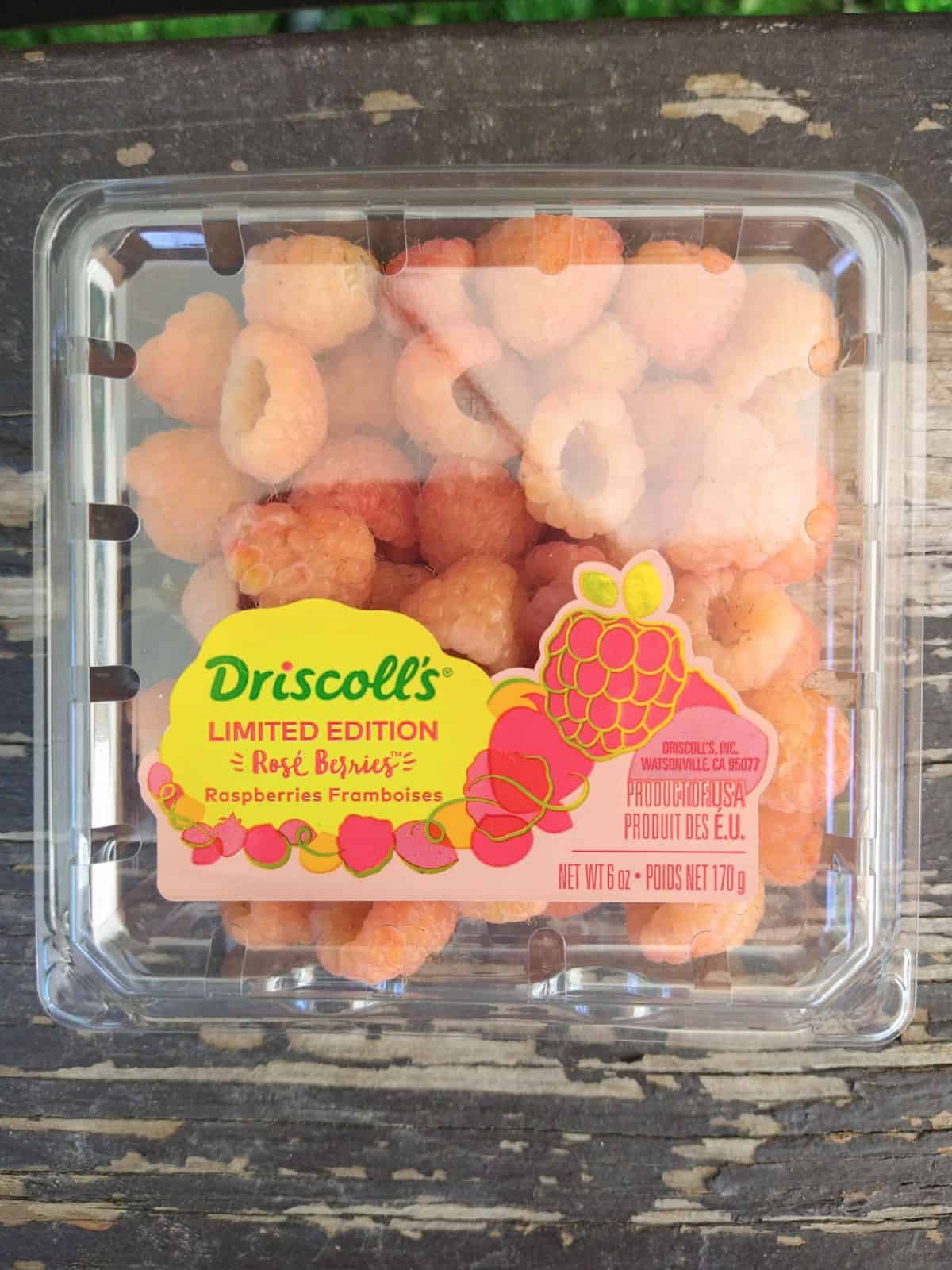 Driscoll's Limited Edition Rose Raspberries in a container on a wood picnic table.